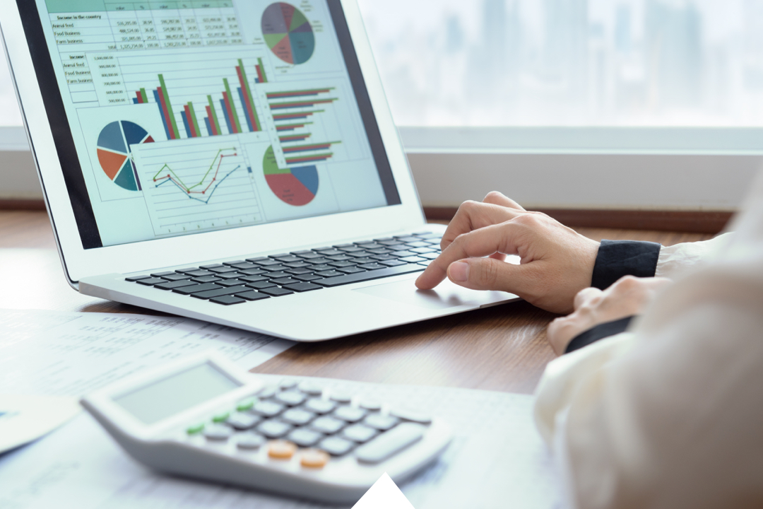 Hands typing on laptop screen with excel file and charts