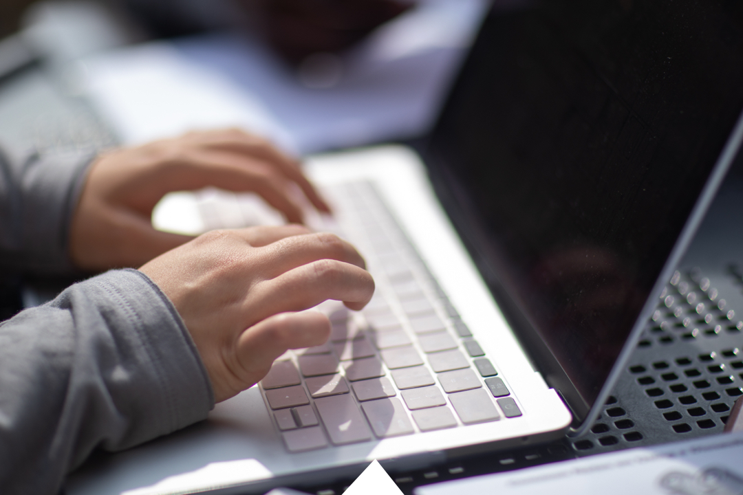 Hands typing on a laptop